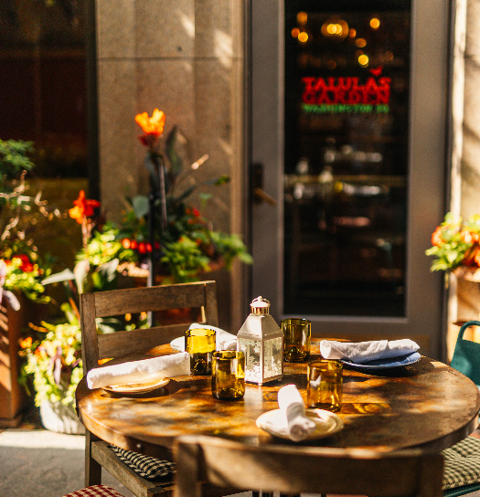 Wooden patio with a table, chairs, and a wall-mounted planter filled with flowers.